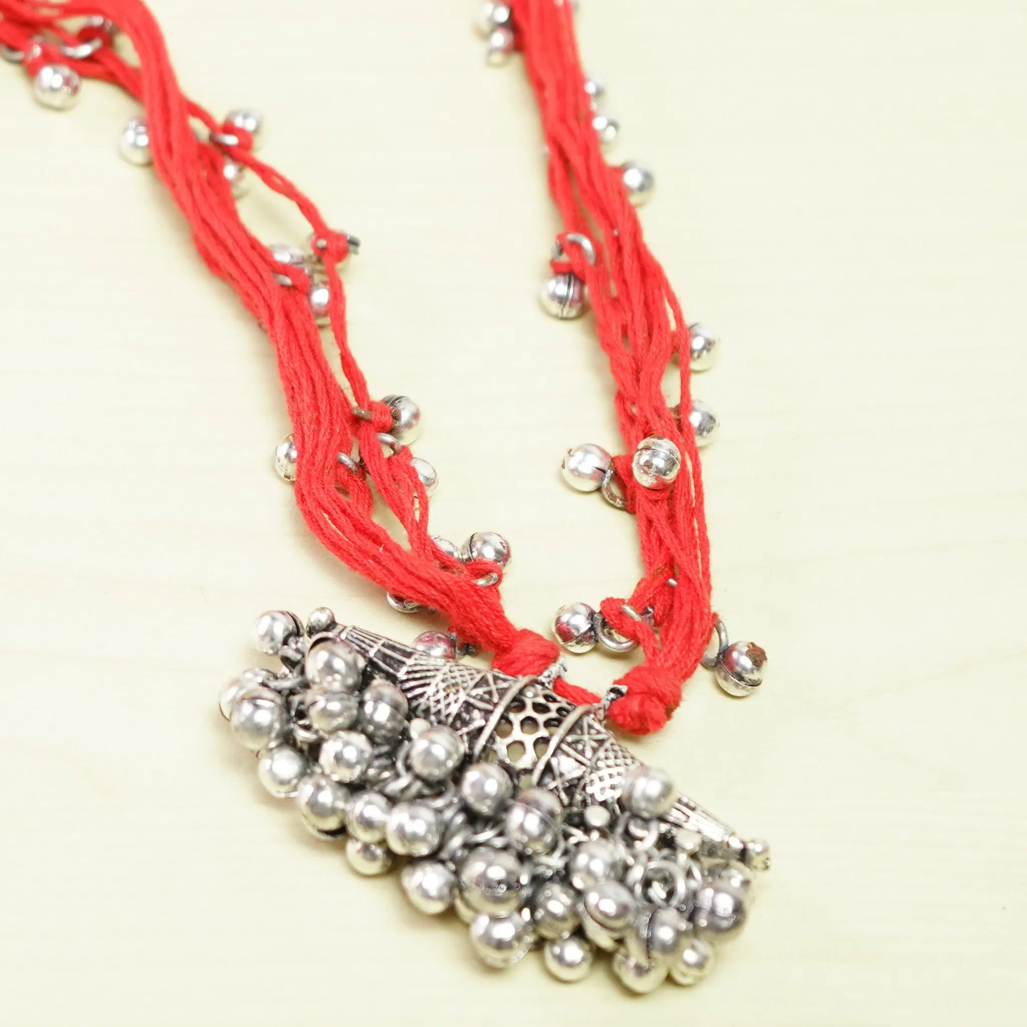 Vibrant Red Thread Neckpiece with Silver Bell Beads and Oval Pendant