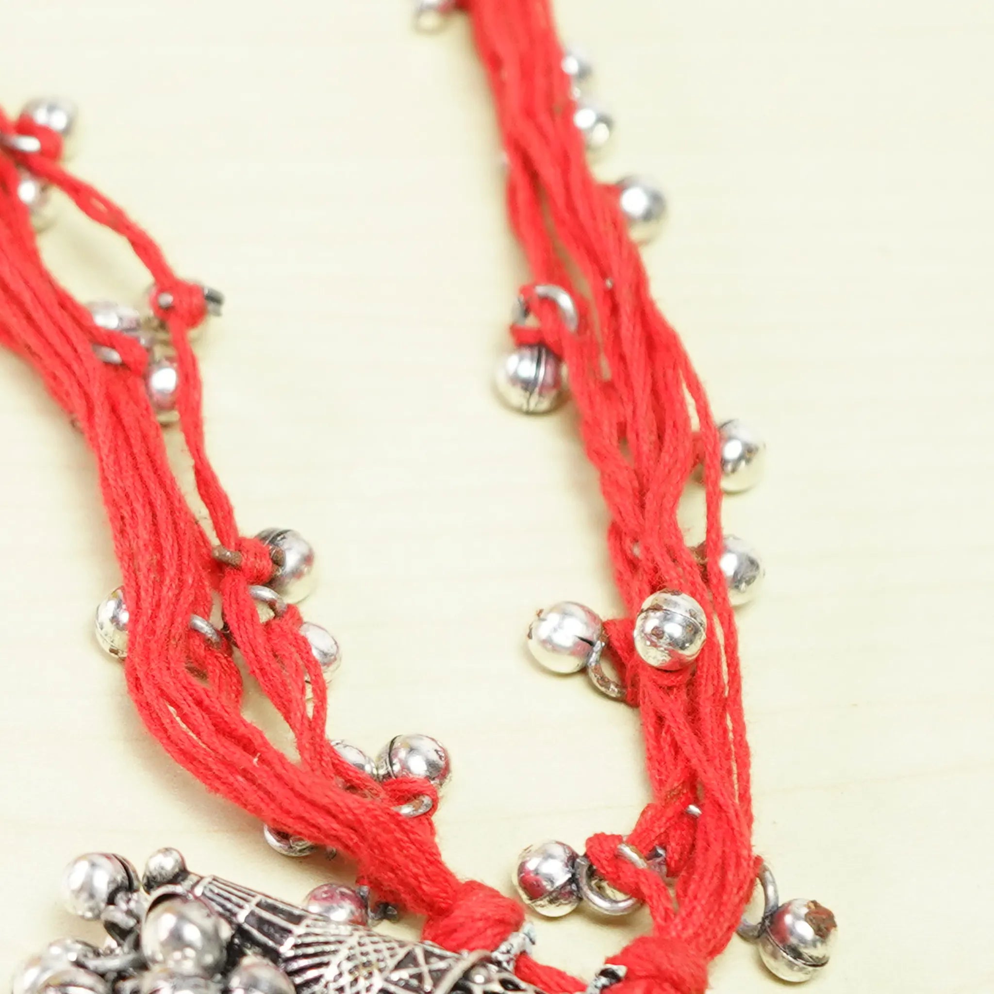 Vibrant Red Thread Neckpiece with Silver Bell Beads and Oval Pendant