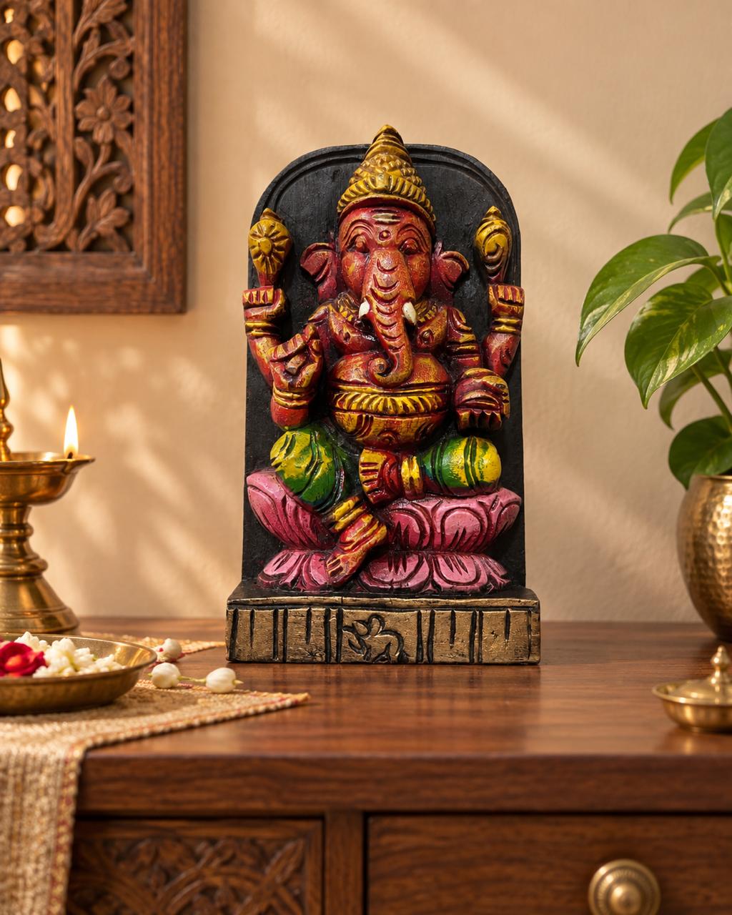 Hand-carved Ganesha wooden sculpture displayed with brass lamp and flowers